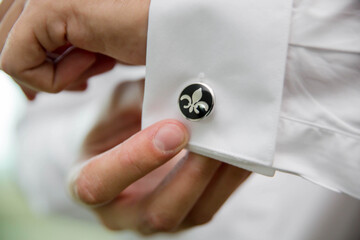Closeup shot of a groom's hand fixing the cufflinks of his white shirt before the wedding ceremony