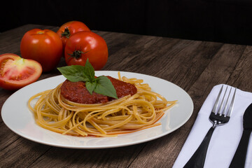 Pasta with red sauce and basil leaves. Tomatoes in the background. Space for text.