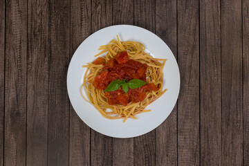 Pasta with rustic tomato sauce and basil leaves. Served on the white plate. Top view photography...