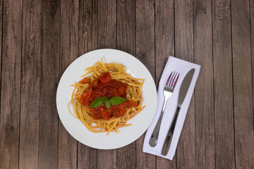 Pasta with rustic tomato sauce and basil leaves. Bavette pasta in red sauce. Top photo with top space for text. Cutlery on napkin. Popular pasta.