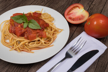 Pasta with rustic tomato sauce and basil leaves. Bavette pasta with red sauce. Red tomatoes. Fork and knife.Gastronomic photo for restaurants.