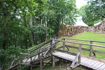 Staircase made of thick wooden planks on a hillside near a stone wall