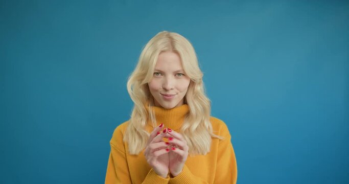 Villain idea. Sly blonde woman conspiring scheming, thinking over tricky plan with cunning expression, pondering revenge or evil prank. Indoor studio shot isolated on blue background