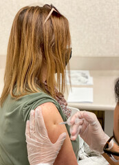 Fototapeta premium Middle aged woman receiving first dose of COVID-19 vaccine