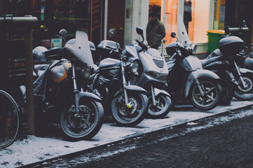 Fototapeta na wymiar motos sur le trotoire recouvertes de neige