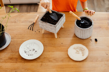 Little gardener loosening soil in ceramic pot