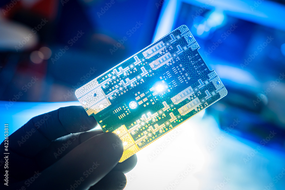Poster computer board in hand of a man. small printed circuit board close-up. bright light shines through c