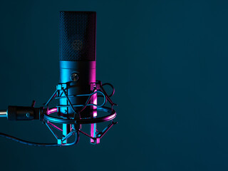 Professional studio microphone. Condenser microphone on a dark background. It is designed for podcasting. Microphone as a symbol for recording audio podcasts. Recording audio podcasts in studio - obrazy, fototapety, plakaty