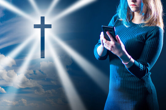 Catholic Cross Next To Girl. Concept - She Is Attending Church Remotely. Remote Catholic Mass App. Catholic Woman With Smartphone. A Girl Watches A Service On Online. Online Christian Mass