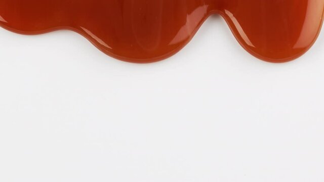 close up of flowing melted caramel sauce macro on white background
