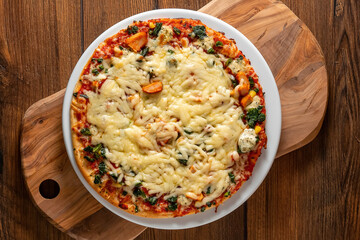 Chicken pizza on a white plate and wooden table. Italian traditional food and fast food product