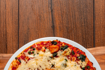 Chicken pizza on a white plate and wooden table. Italian traditional food and fast food product