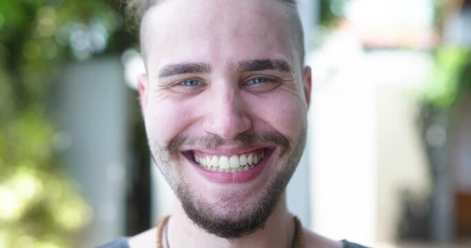 Closeup of a smiling young latin caucasian man. Brazilian guy. Joy, positive and love. Beautiful blue eyes. 4K.