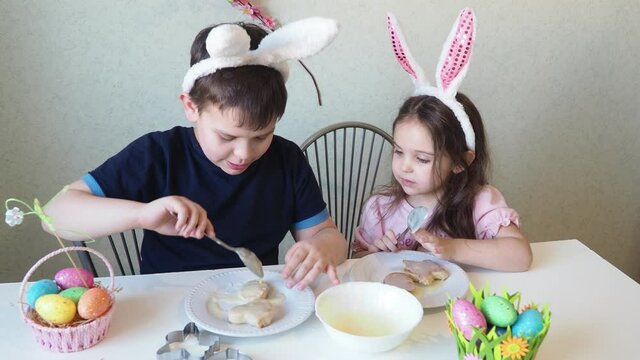 boy and girl are preparing cookies for easter, laughing. Having fun on Easter egg hunt. Child boy and girl wearing bunny ears and painting eggs. colorful eggs