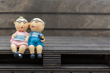Plastic figures of an old, in love couple sits contentedly, healthy and in a good mood on a brown...