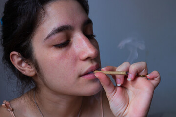 Obraz premium Woman smoking marijuana on plain background