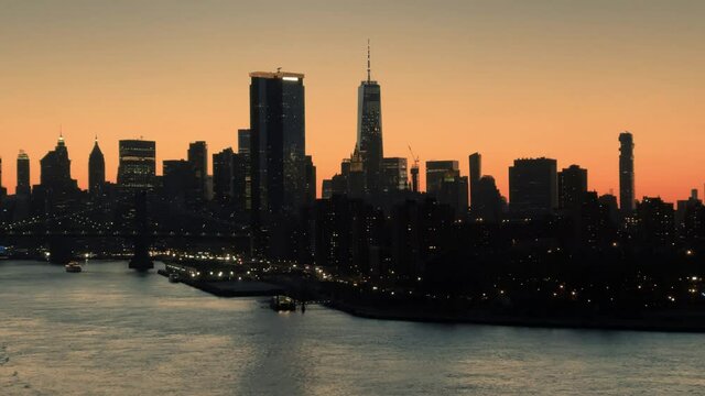 Manhattan skyline downtown silhouette buildings lights on East River water Brooklyn Bridge New York City NYC