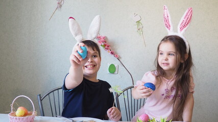 boy and girl are preparing cookies for easter, laughing. Having fun on Easter egg hunt. Child boy and girl wearing bunny ears and painting eggs. colorful eggs