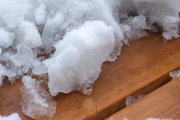 Close up full frame abstract texture background of partially shoveled deep snow accumulated on a cedar wood deck floor  © Cynthia