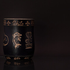 Mate negro grabado con bombilla plateada y fondo negro.