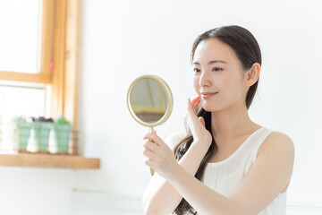 手鏡を見る若い女性