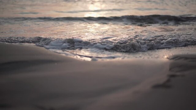 Ocean waves rolling on the beach sand at sunset - Close up