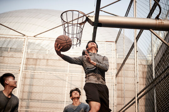 Young Asian Men Playing Basketball Outdoors