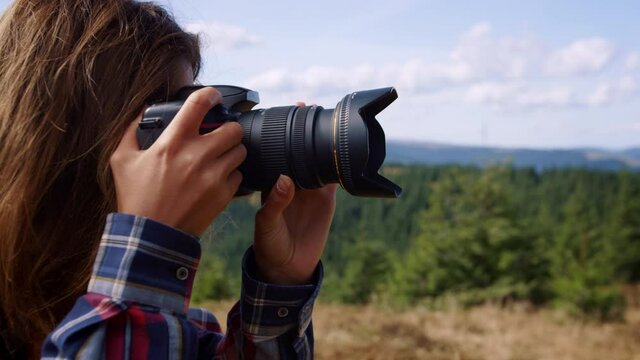 Photographer taking pictures of landscape. Woman using photo camera in mountains