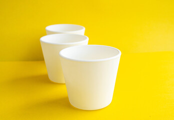 White pots empty on a yellow background. Empty jars on the table.