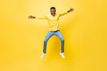 Fototapeta na wymiar Young excited African man jumping with outstretched hands isolated on yellow studio background