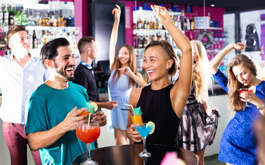 Happy cheerful positive man with woman are drinking cocktails on corporate party.