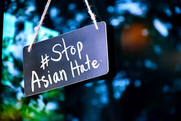 English texts “Please Stop Asian Hate” on label in front of the Asian’s shop, concept for calling international community to stop hurting and hating Asian people. Selective focus on texts.