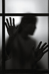 dramatic silhouette of blurred woman shadow behind window glass