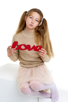 Preteen girl holding red word Love. Photo session in the studio