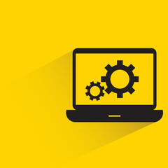 laptop and gears with shadow on yellow background