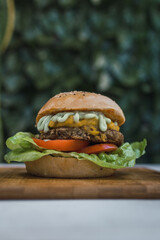Vegan lentils burger with cheddar and parsley-based sauce. Light background, copy space. Vegan food concept.