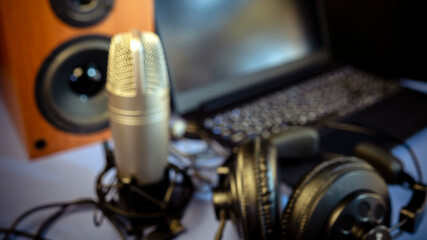 Blured background. Studio microphone, headphones, speakers and computer. Home studio recording for sound mixing, sound design and music production.
