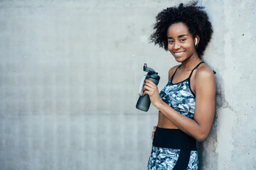 Athletic woman drinking water after work out outdoors.