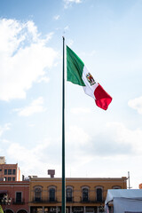 Vertical image of the flag of Mexico on a flagpole. Downtown Leon, Guanajuato. Urban concept.