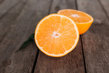 Halves of orange fruit on gray wooden background. Orange pulp and green leaves