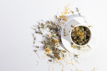 dry medicinal herb thyme and calendula, in a white cup on a white background top view