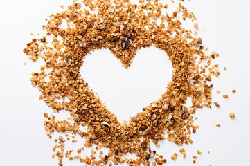 homemade granola with nuts in the form of a love heart symbol on a white table, top view