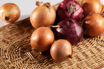 dry multicolored onion on a wicker stand and white background