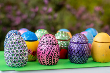 Hand-made Easter eggs on a green pedastal in front of purple lavender flowers.