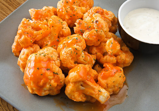 buffalo-style cauliflower piled up on a plate with ranch dipping sauce