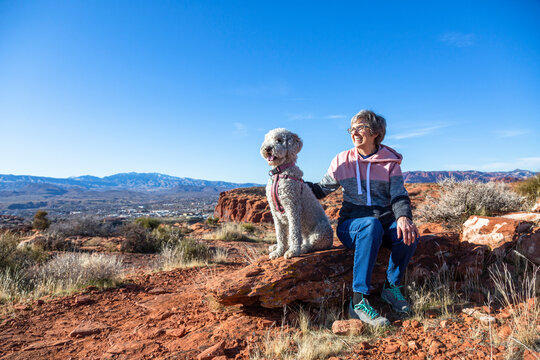 Happy senior woman on an outdoor hike with her dog. Enjoying nature on a sunny day. Enjoying a scenic overlook in St. George, Utah