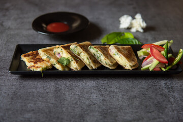 Close up of popular Mexican dish quesadilla on a black plate with use of selective focus.