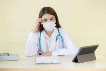 Asian female doctor Sitting in the examination room wearing a mask and pondering in  health care,pollution PM2.5,new normal and coronavirus protection concept.