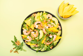 Mango, Shrimps and Avocado Salad with Walnut, Spinach and Arugula. Healthy Eating food concept Top view, lime green background