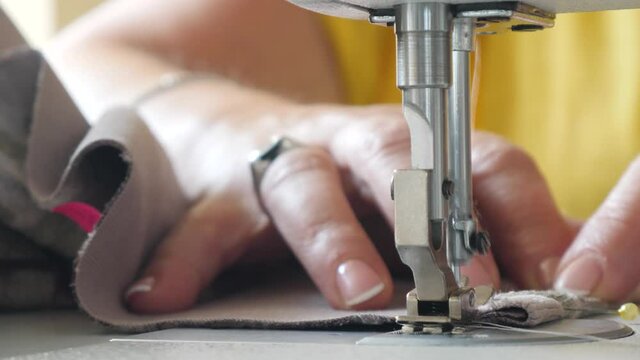 Processing edge tulle lace curtains on sewing machine. Senior female sewing cloth. Work table of tailor. Tailoring process or repairing clothes